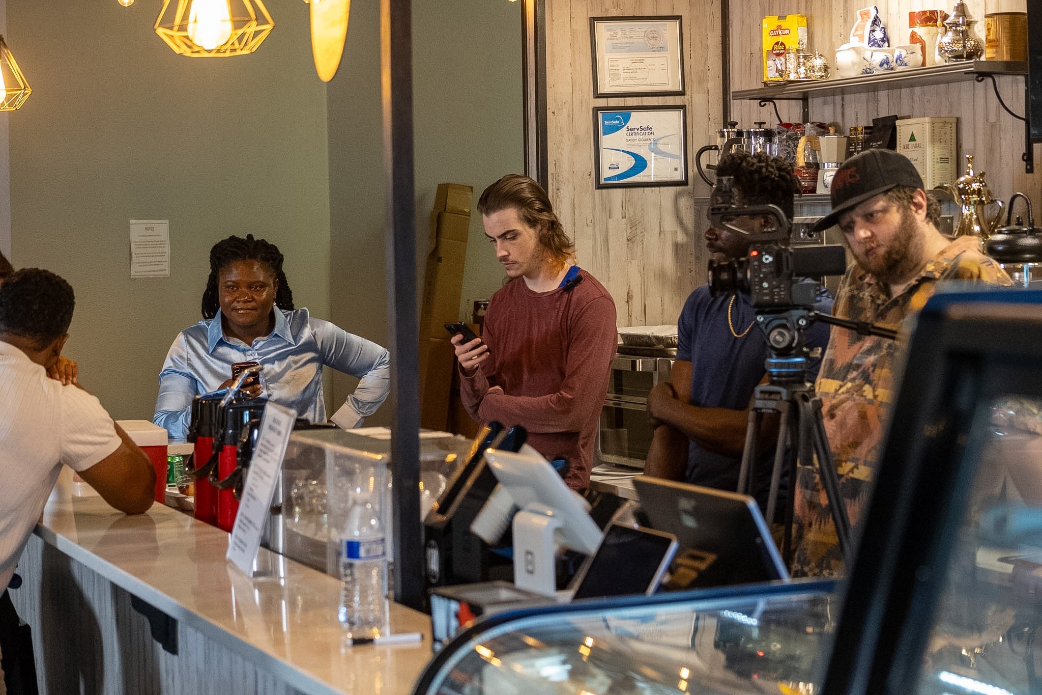 Between Two Lives crew gathered around the camera in the coffee shop