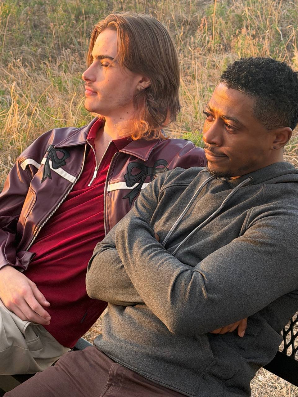 Two men sitting side by side outdoors at sunset in Between Two Lives