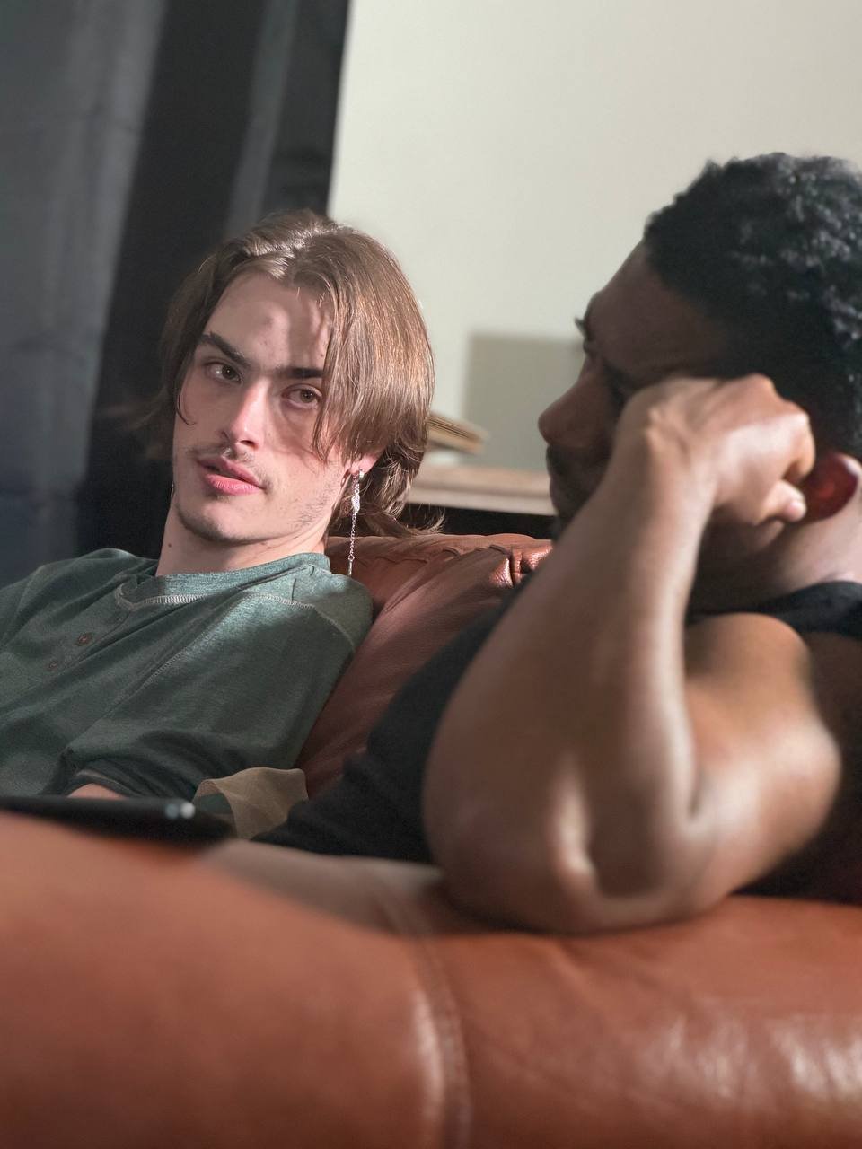 Two actors relaxing on a couch between takes, one looking into the camera